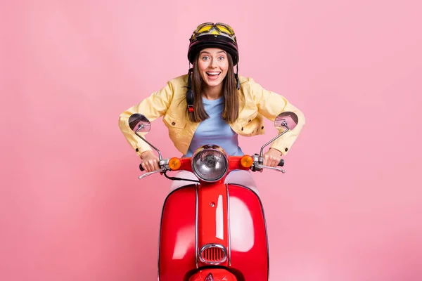 Foto van jong gelukkig opgewonden mooi meisje vrouw rijden rood motorfiets snel dragen geel helm geïsoleerd op roze kleur achtergrond — Stockfoto