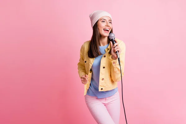 Foto de linda linda chica cantar canción en el karaoke usar pantalones de chaqueta gorra aislado en fondo de color rosa pastel —  Fotos de Stock