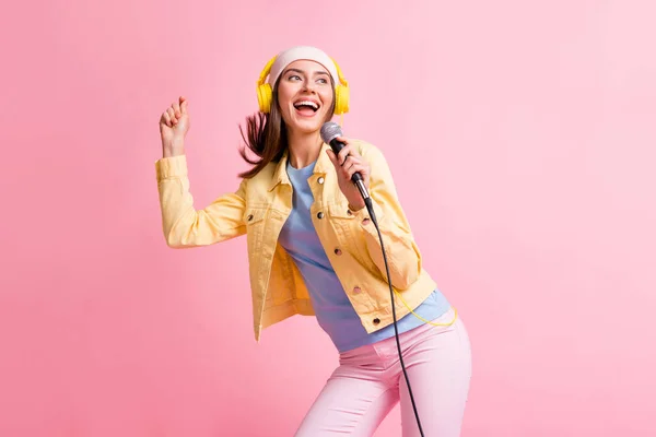 Foto av trevlig söt dam lyssna musik dans sjunga bära mössa hörlurar jacka byxor isolerad på rosa färg bakgrund — Stockfoto