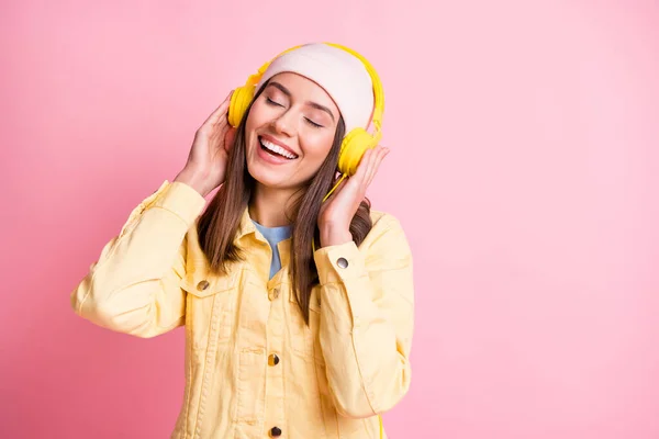 Retrato de joven encantador escuchar música agradable tocar auriculares ojos cerrados aislados sobre fondo de color rosa — Foto de Stock