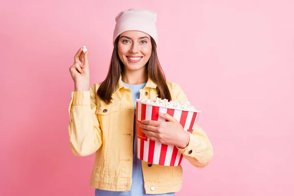 Porträtt av bedårande rolig person hålla popcorn njuta ögonblick bära mössa isolerad på rosa färg bakgrund — Stockfoto