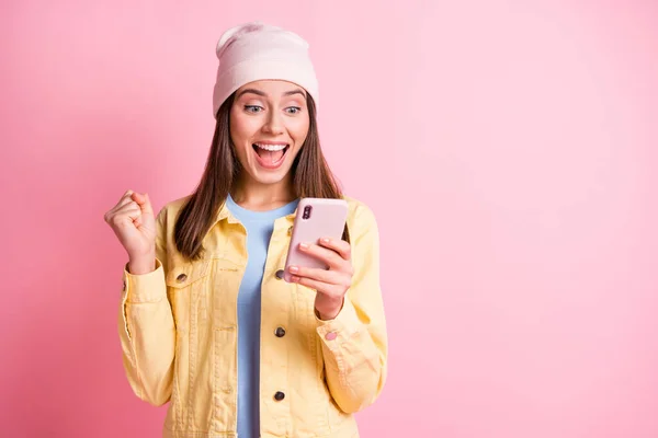 Foto de senhora surpreendida ganhou aposta punho olhar telefone boca aberta headwear isolado no fundo cor-de-rosa pastel — Fotografia de Stock