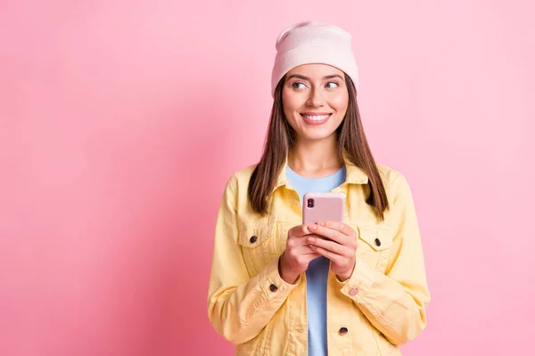 Foto de sonho alegre bonita menina olhar stand espaço vazio segurar telefone isolado no fundo cor-de-rosa — Fotografia de Stock