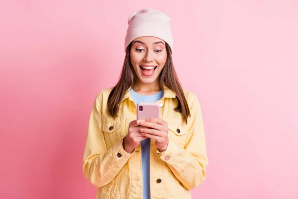 Foto de menina de cabelos castanhos maravilhados segurar olhar telefone reação surpresa como isolado no fundo cor-de-rosa — Fotografia de Stock