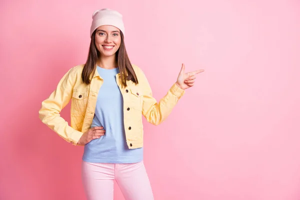 Foto van bruin haar gelukkig meisje punt lege ruimte hand taille dragen geel jasje geïsoleerd op roze kleur achtergrond — Stockfoto