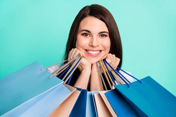 Foto de mujer joven sonrisa feliz manos tacto mejillas sostener bolsas shopaholic venta cliente aislado sobre fondo de color turquesa —  Fotos de Stock