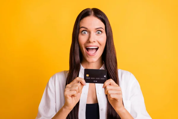 Portrait of pretty astonished lady arms hold banking debit card open mouth isolated on yellow color background — Stock Photo, Image