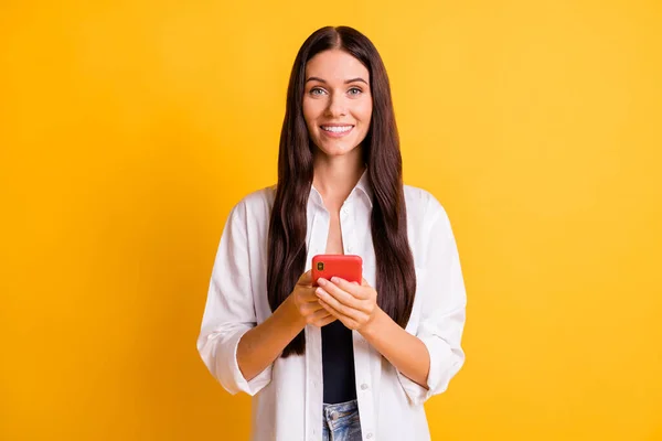 Fotografie rozkošné pozitivní dáma zářící úsměv vzhled fotoaparát držet telefon izolované na žlutém pozadí — Stock fotografie