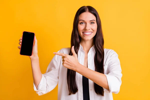 Фото досить веселої леді прямий палець, що показує телефон, що відображає зубну посмішку ізольовано на жовтому кольоровому фоні — стокове фото