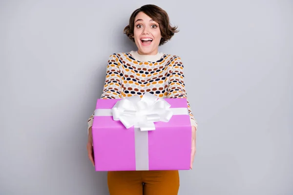 Retrato de menina alegre atraente segurando em mãos dando-lhe grande presente isolado sobre fundo de cor pastel cinza — Fotografia de Stock