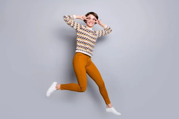 Pleine longueur corps taille vue de attrayant drôle gai fille sautant montrant v-signe avoir du plaisir isolé sur fond gris couleur pastel — Photo