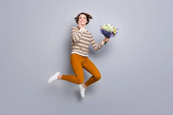 Comprimento total tamanho do corpo vista de linda menina alegre maravilhada pulando segurando em mãos flores isoladas sobre fundo de cor pastel cinza — Fotografia de Stock
