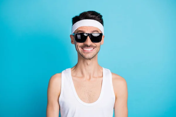 Retrato de chico deportivo de buen humor en gafas de sol mira cámara aislada sobre fondo de color azul — Foto de Stock
