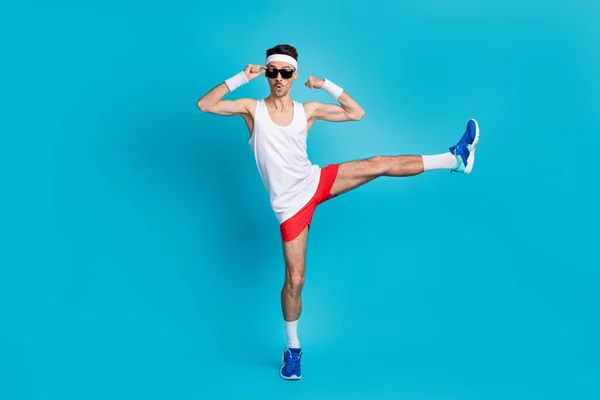 Full size foto van sportieve jongen tonen armen training resultaat dragen polsbandje sneakers shorts geïsoleerde blauwe kleur achtergrond — Stockfoto