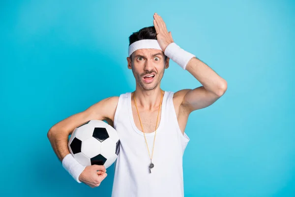 Фото изумленного футболиста, держащего шар касательной головой руки носить белый синглет изолирован на синем фоне цвета — стоковое фото