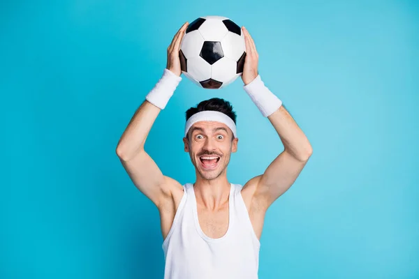 Фото изумленного футболиста человек поймать мяч крик носить белый топ танк изолированы на синем фоне цвета — стоковое фото
