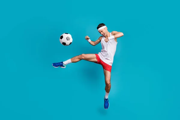 全长的体育青年男子跳起来空中踢足球的照片，隔离在淡蓝色的背景下 — 图库照片