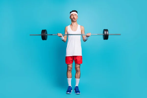 Foto des jungen Sportlers heben schwere Langhantel Grimassen Übung Körperpflege isoliert über blauem Hintergrund — Stockfoto