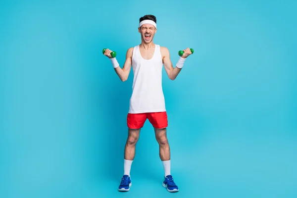 Full size foto di giovane sportivo fare esercizio urlare pesante dumbells allenamento isolato su sfondo di colore blu — Foto Stock
