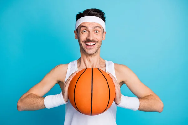 Fotografie mladého vzrušeného muže šťastný pozitivní úsměv držet míč připraven hrát izolované přes modré pozadí — Stock fotografie