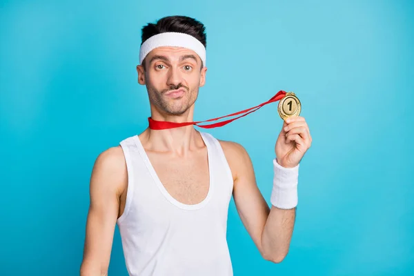 Foto de joven deportista serio celebrar medalla de oro ganar la competencia victoria aislado sobre fondo de color azul — Foto de Stock