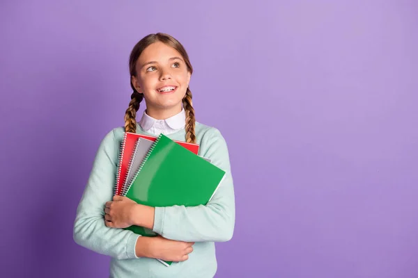 Photo portrait of dreamy girl holding notebooks in hands looking at blank space isolated on vivid purple colored background — Stock Photo, Image