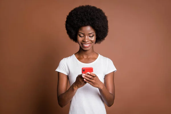 Foto portrét modelu s úsměvem pomocí mobilní aplikace procházení internetu izolované na hnědém pozadí — Stock fotografie