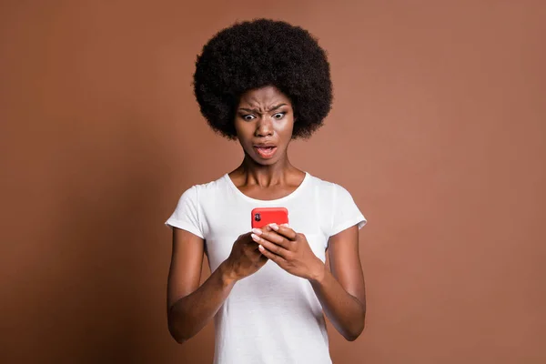 Retrato de persona de piel oscura descontenta impresionada boca abierta mirando fijamente teléfono aislado sobre fondo de color marrón — Foto de Stock