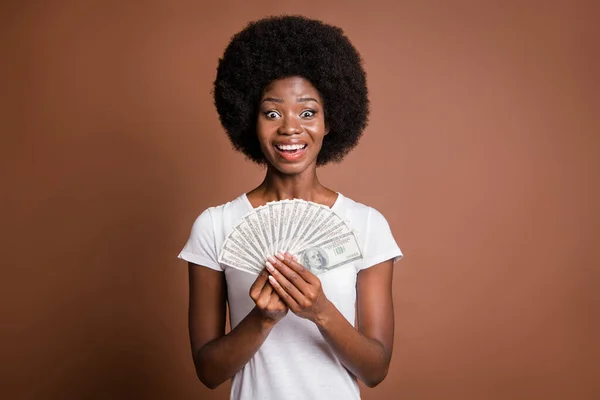 Zdjęcie portret kobiety pokazujące pieniądze gotówki banknotów dolara uśmiechając się overjoyed bogate izolowane na brązowym tle koloru — Zdjęcie stockowe