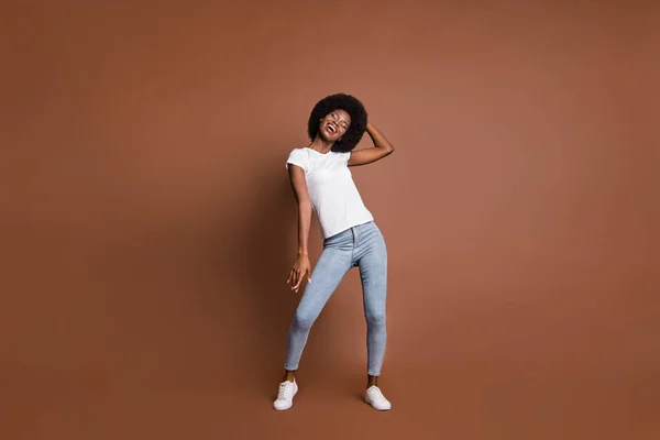 Foto de inspirada menina dança fechar os olhos desgaste branco t-shirt jeans tênis isolado marrom cor fundo — Fotografia de Stock