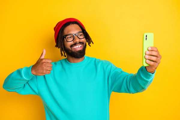 Foto do jovem homem africano feliz sorriso positivo mostrar thumb-up fazer celular selfie isolado sobre fundo de cor amarela — Fotografia de Stock