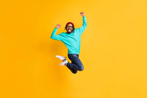 Foto de perfil de tamaño completo de tipo optimista morena salto usar gafas jersey pantalones vaqueros aislados sobre fondo de color amarillo —  Fotos de Stock