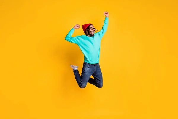 Foto de perfil de tamaño completo de morena hooray chico salto desgaste gorra gafas jersey jeans zapatillas aisladas sobre fondo de color amarillo —  Fotos de Stock