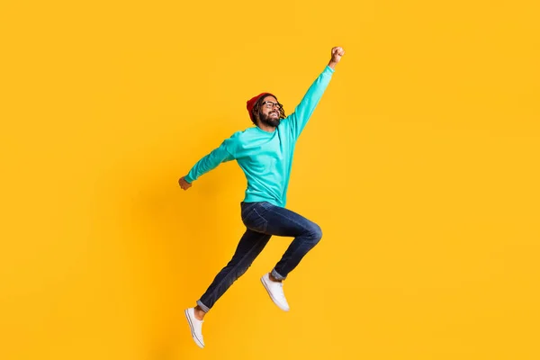 Foto lateral de perfil de cuerpo completo del joven africano feliz sonrisa positiva saltar superhéroe aislado sobre fondo de color amarillo —  Fotos de Stock