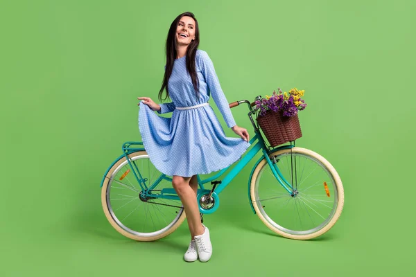 Foto de bonito senhora desgaste roupas pontilhadas sorrindo segurando vestido saia bicicleta olhando espaço vazio isolado cor verde fundo — Fotografia de Stock