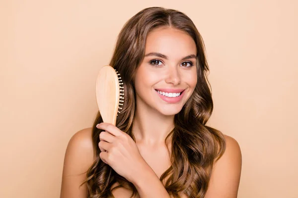 Foto de joven hermosa sonriente hermosa hermosa mujer cepillando el pelo ondulado largo aislado sobre fondo de color pastel — Foto de Stock