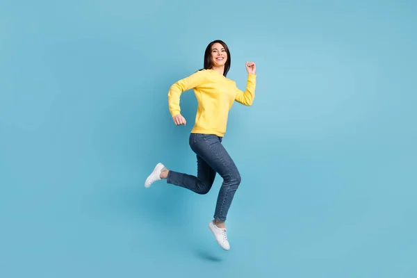 Foto de tamaño completo de agradable optimista morena largo peinado señora correr usar camisa jeans zapatillas aisladas sobre fondo de color azul —  Fotos de Stock
