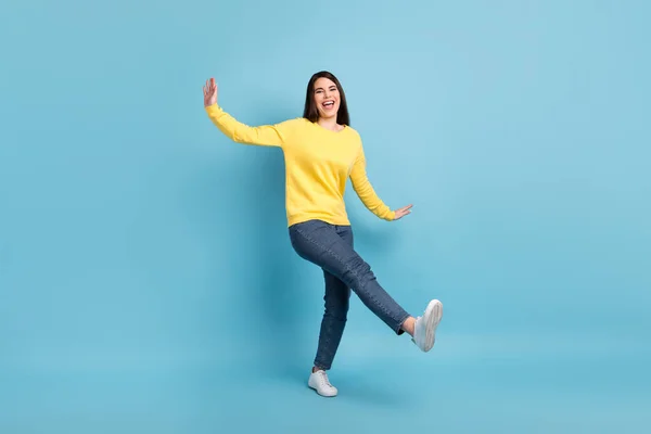 Foto van funky mooie dame dans verhogen handen open mond dragen gele trui jeans sneakers geïsoleerde blauwe achtergrond — Stockfoto