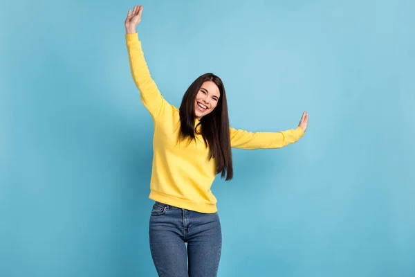 Foto van zorgeloos funky schattig dame dans veel plezier verhogen handen dragen geel jumper geïsoleerde blauwe achtergrond — Stockfoto