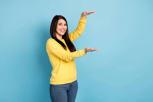 Foto van mooie optimistische brunette lang kapsel dame tonen grootte dragen geel shirt geïsoleerd op helder blauwe kleur achtergrond — Stockfoto