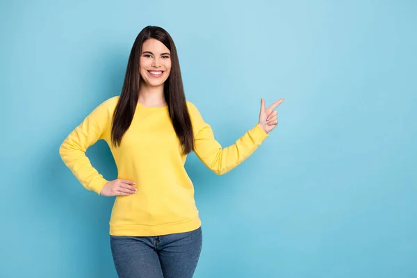 Portret van mooie optimistische brunette lang kapsel dame punt lege ruimte dragen geel shirt geïsoleerd op helder blauwe kleur achtergrond — Stockfoto