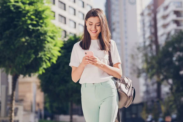 Foto retrato de estudiante con mochila escribiendo sms usando teléfono móvil caminando por la calle de la ciudad hasta la universidad — Foto de Stock