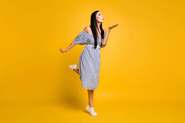 Volledige lengte foto van charmante zoete jonge dame dragen gestreepte jurk verzenden kus arm lege ruimte geïsoleerde gele kleur achtergrond — Stockfoto