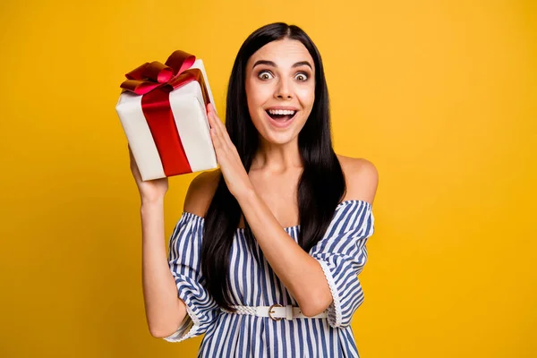 Foto de la joven encantadora excitada usar vestido a rayas adivinar regalo dentro de la caja de regalo aislado color amarillo fondo —  Fotos de Stock
