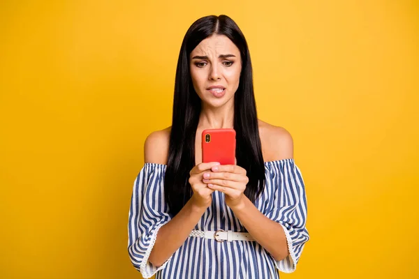 写真の動揺有罪若い女性の着用ストライプ保持現代的なデバイスかむ唇隔離された黄色の背景 — ストック写真