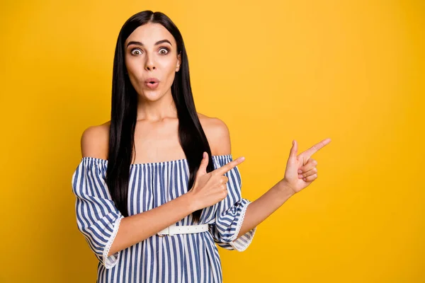 Photo of shiny impressed young lady wear striped dress pointing two fingers empty space isolated yellow color background — Stock Photo, Image