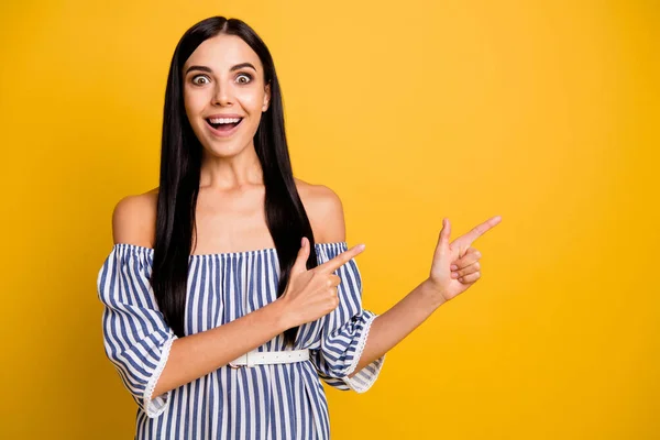 Foto di scioccato divertente giovane donna vestita off-spalla vestito che indica lo spazio vuoto due dita isolato colore giallo sfondo — Foto Stock
