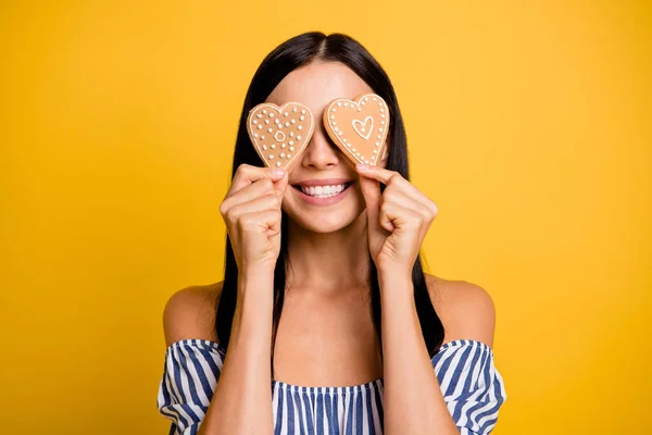 Foto de adorável encantador jovem senhora desgaste listrado sorrindo dois bolos fechar os olhos isolado cor amarela fundo — Fotografia de Stock