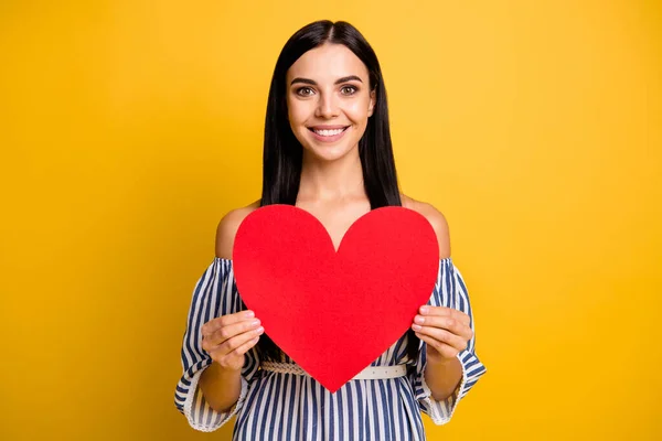 Foto de jovem muito adorável usar roupas listradas segurando grande papel vermelho coração sorrindo isolado cor amarela fundo — Fotografia de Stock