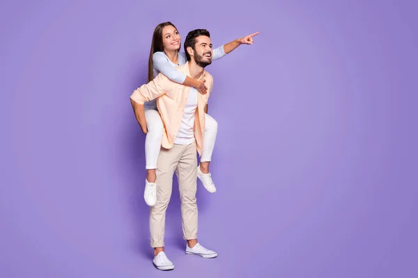 Full length profile portrait of two persons piggyback lady direct finger empty space isolated on purple color background — Stock Photo, Image